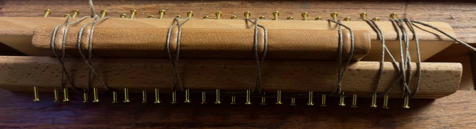 A deluxe copy of Mornings at Jack Pine in the finishing press setting the raised bands on the spine.